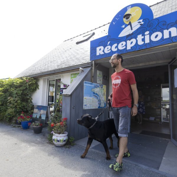 Rottweiler et son maitre sortant de la réception du Camping Sites et Paysages LA TORCHE - Finistère - Bretagne - Plomeur - Animaux acceptés - Chiens acceptés - EmmèneTonChien.com