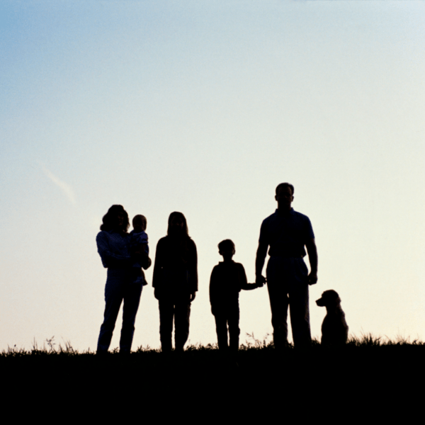 Un chien et sa famille devant le lever du soleil en été