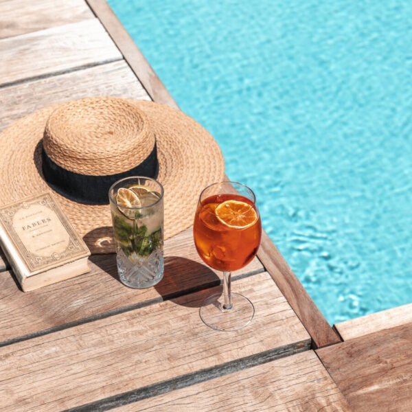 Chapeau, livre et cocktail au bord de la piscine de L'Ermitage Hôtel à Lyon dans le Rhône dans l'Auvergne Rhône-Alpes