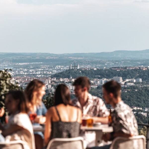 Des amis assis autour d'une table sur une terrasse avec une magnifique vu depuis L'Ermitage Hôtel à Lyon dans le Rhône dans l'Auvergne Rhône-Alpes