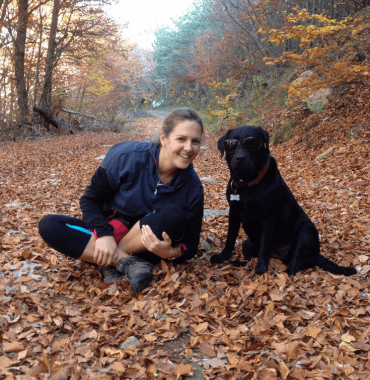 Une femme sportive et son chien sur un chemin de randonnée en automne dans la forêt dans une des plus belles destinations de vacances dog-friendly