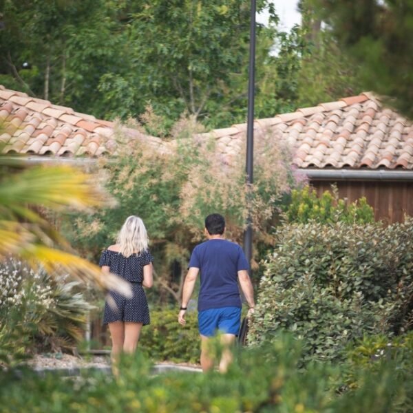 Un couple se balade entre les lodges du Domaine du Ferret en Gironde en Nouvelle-Aquitaine à Lège-Cap-Ferret