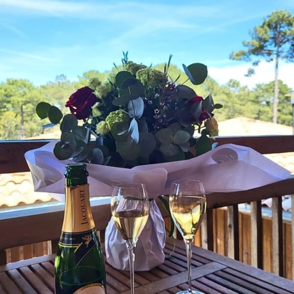 Champagne et bouquet de roses pour un couple sur la table de leur lodge du Domaine du Ferret en Gironde en Nouvelle-Aquitaine à Lège-Cap-Ferret