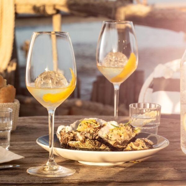 Table avec deux verres de Vermouth et une assiette d'huîtres sur une table ensoleillée à La Maison Noilly Prat dans l'Hérault en Occitanie à Marseillan