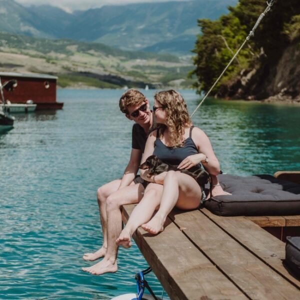 Couple avec un teckel dans les bras assis sur le pont d'une des Toues Cabanées du Lac dans les Hautes-Alpes en Provence-Alpes-Côte d'Azur à Le Sauze-du-Lac