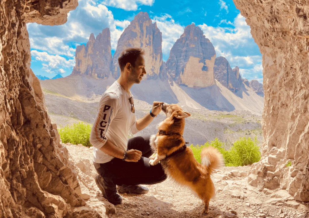 Randonneur avec son chien dans une grotte devant les sommets des Tre Cimes en Italie