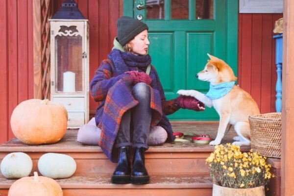 Une femme et son chien devant leur location de vacances en automne dans une des meilleures destinations