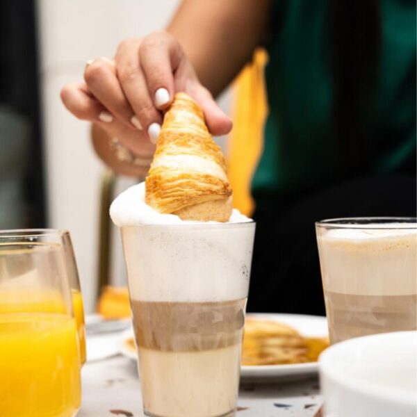 Une personne trempe son croissant dans un café au Bar Anamorphose by Graphik Hôtel à Paris en île-de-France