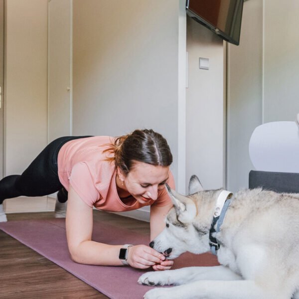 Un femme faisant de l'exercice avec son chien allongé à côté dans une chambre de l'Appart'City Confort Pau *** à Pau dans les Pyrénées-Atlantiques en Occitanie