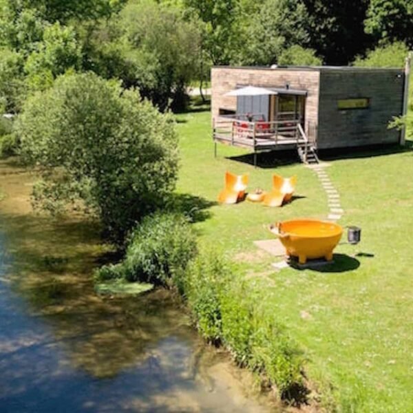 Vue d'extérieur de haut sur le cube, la rivière, le salon de jardin , le bain et le jardin du Gîte insolite du Domaine Pont Roche en Côte d'or en Bourgogne-Franche-Comté à Frénois