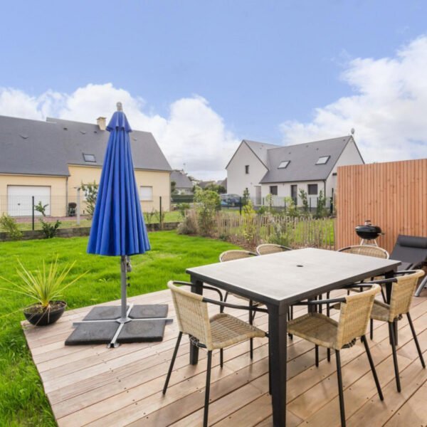 La table du jardin sur la terrasse avec un parasol du Gîte Face au vent à Port-Bail-sur-Mer dans la Manche en Normandie