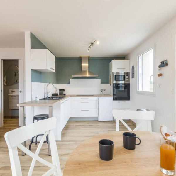 Une salle à manger et la cuisine équipée du Gîte Face au vent à Port-Bail-sur-Mer dans la Manche en Normandie