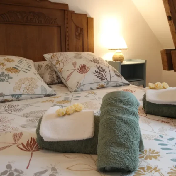 Une des chambre double avec les serviettes roulées et des roses blanches du Gîte La Bignone à Saint-Marcouf dans la Manche en Normandie