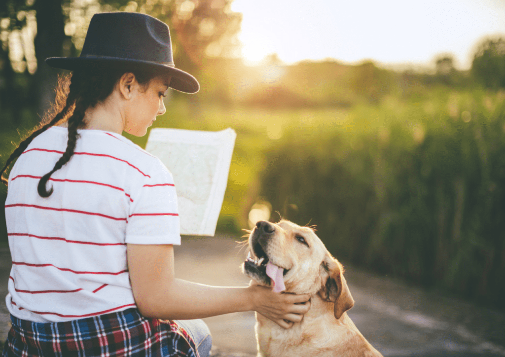 une femme caresse son chien en étudiant la carte de l'itinéraire clé en main avec activités et hébergements chien accepté