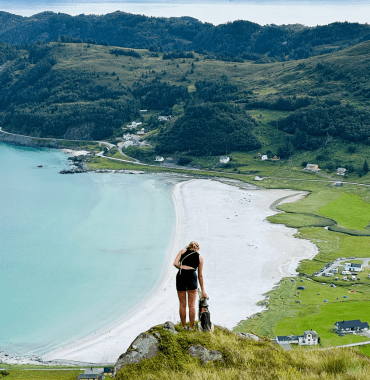 voyageuse avec son chien devant une plage en Norvège l'été pendant un road-trip