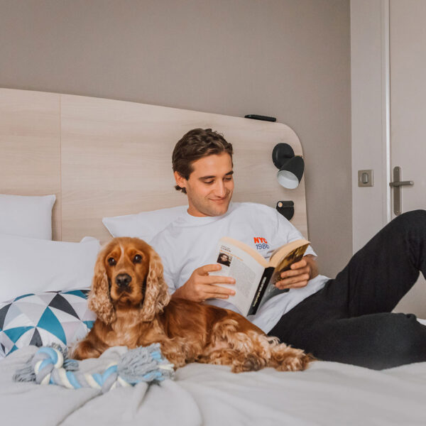 un homme et son chien sur le lit dans la chambre de l'appart city classic blois