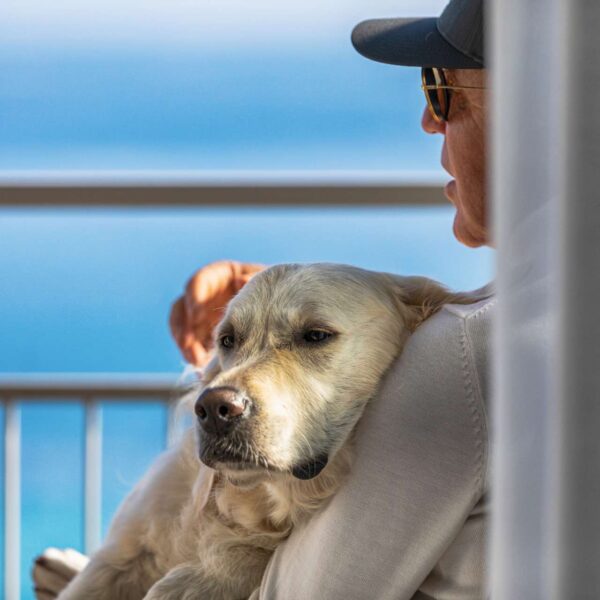 Chien dans les bras de son maître qui profite de la vue sur la mer depuis la terrasse de Baba Residences à Alassio en Italie