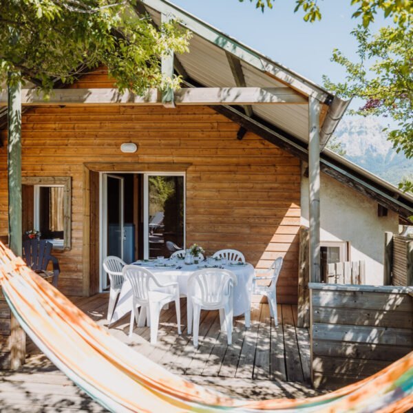 Terrasse table, chaises et Hamac d'un hébergement avec vue sur le lac et les montagnes au camping Sunelia La Presqu'île **** dans les Hautes-Alpes en Provence-Alpes-Côte d'Azur à Prunières