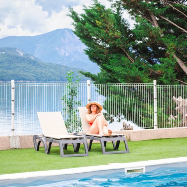 Piscine et transat avec vue sur le lac Serre-Ponçon et sur les Alpes du camping Sunelia La Presqu'île **** dans les Hautes-Alpes en Provence-Alpes-Côte d'Azur à Prunières