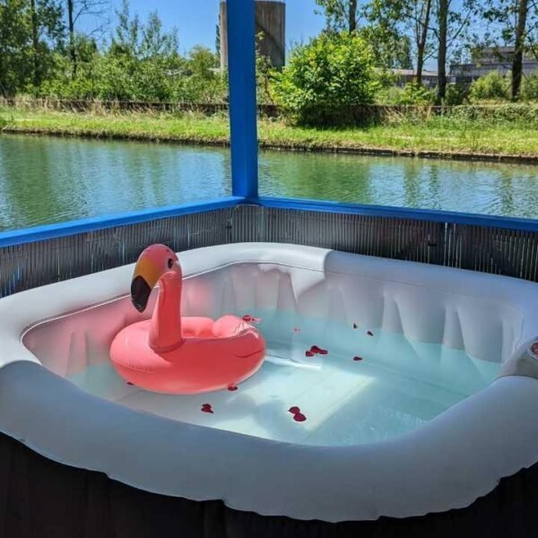 Le jacuzzi privatif avec une bouée flamant rose et des pétales de roses du Cottage flottant insolite à Saint-Jean-de-Losne en Côte d'Or en Bourgogne-Franche-Comté