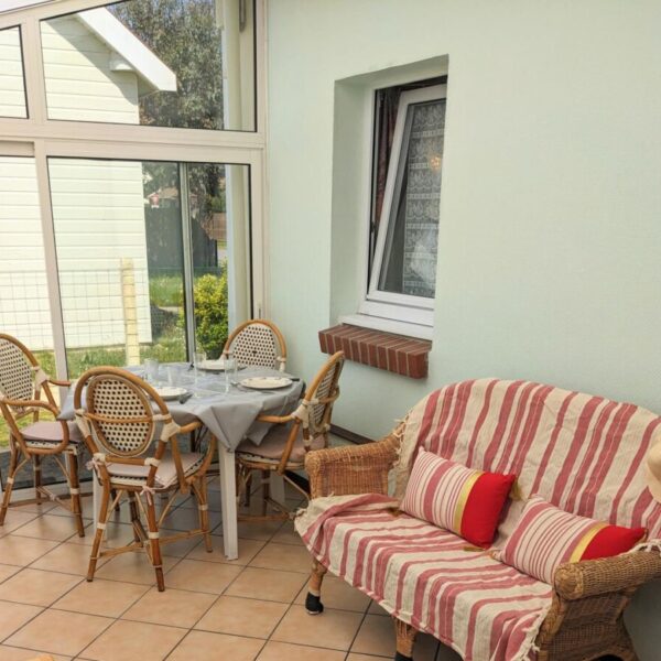 Canape et table avec chaises sur la veranda au Gîte - Un Brin d'Espoir à Fort Mahon Plage à Somme en Hauts de France